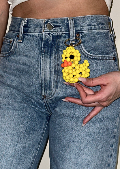 Person wearing blue jeans holding a yellow rubber duck keychain.