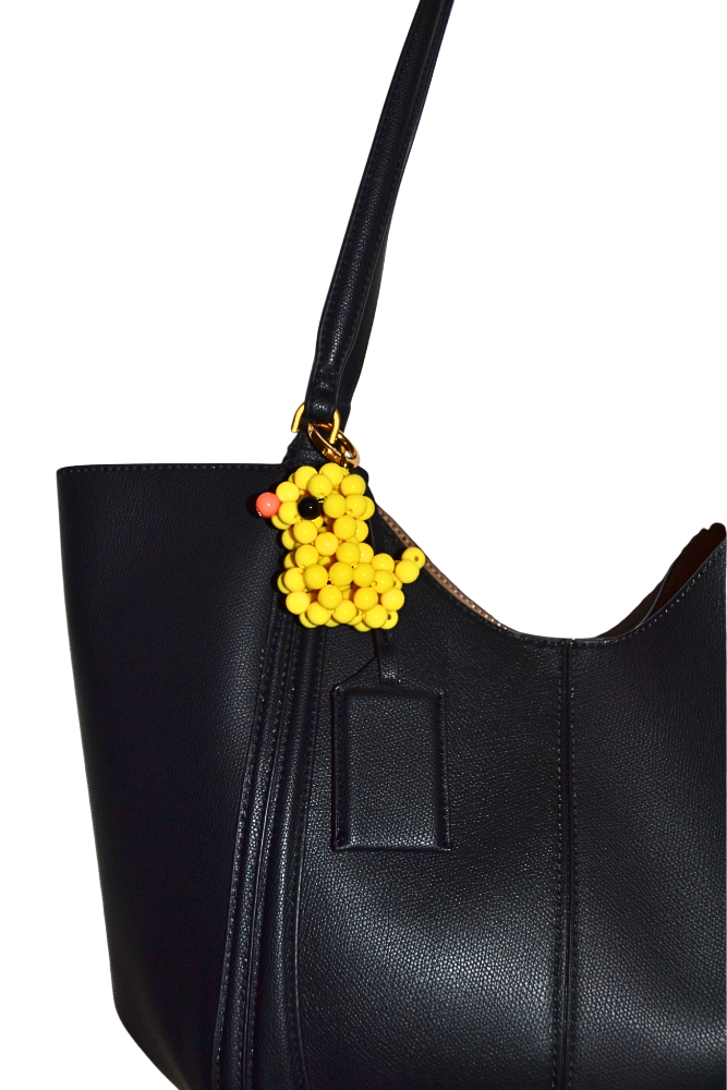 Black handbag with a colorful duck charm on a white background