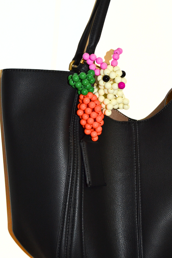 Black handbag with colorful beaded accessory on a white background