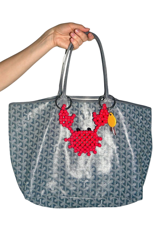 Gray tote bag with red crab design held by a hand on a white background